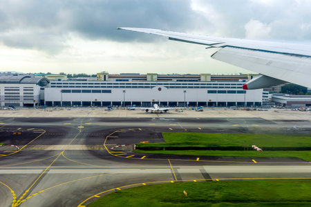 Singapore - May 31, 2024: View of an airplane wing and airport terminal at Singapore Changi Airport, highlighting the bustling operations and infrastructure of one of the world's busiest airportsのeditorial素材