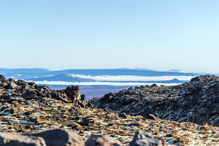 Rocky Volcanic Terrain with Distant Cloud Layer and Mountainsの写真素材