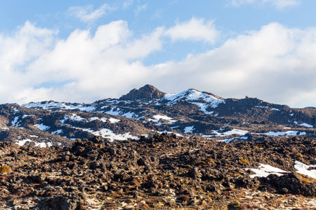 A rugged mountain range dotted with patches of snow under clear blue skiesの写真素材