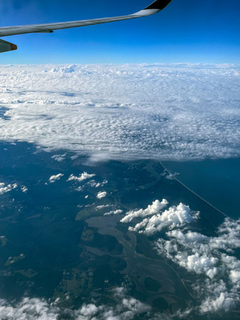 High Altitude View of Clouds and Coastal Landscape from Airplaneの写真素材