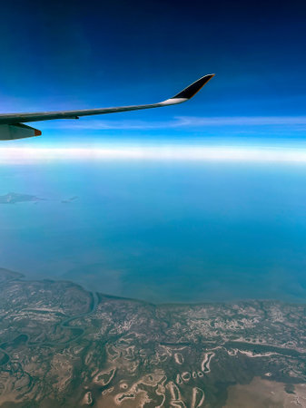 Expansive Aerial View of Coastal Marshlands and Ocean from Airplane Windowの写真素材