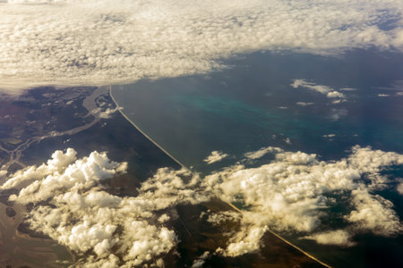 Aerial View of Coastal City and Cloud Formations from Airplaneの写真素材