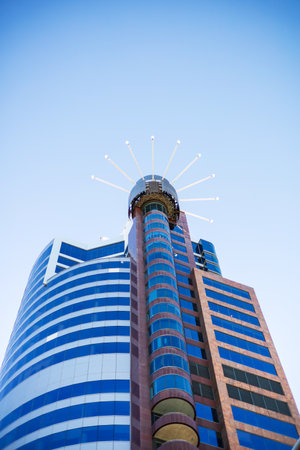 A striking modern skyscraper with a unique circular design element, reflecting the blue skies of Wellington, New Zealandの写真素材