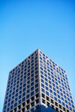 A modern skyscraper with a striking grid pattern facade against a clear blue sky in Wellington, New Zealandの写真素材