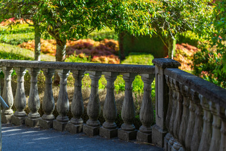 A vintage stone balustrade beautifully framed by lush greenery and dappled sunlight in a tranquil garden settingの写真素材