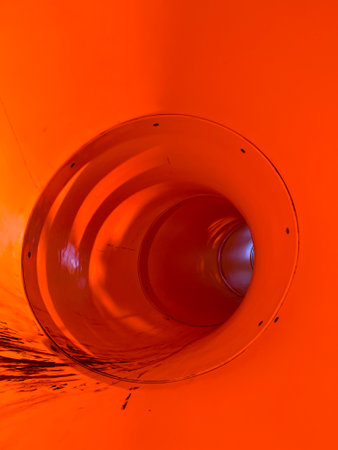 Inside View of a Bright Orange Playground Tunnel Slideの写真素材