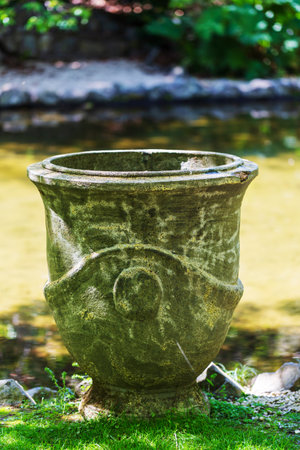 Weathered Stone Planter by Reflective Pond in Garden Settingの写真素材