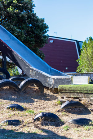 Outdoor Playground Slide with Worn Tires and Grassの写真素材