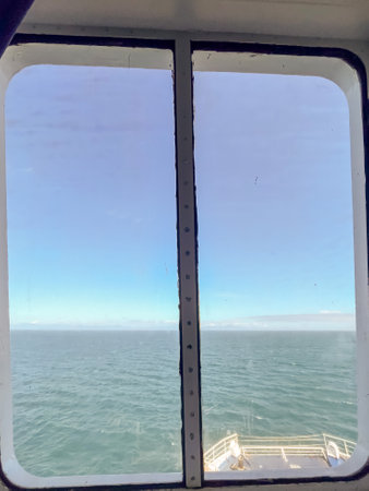 A scenic view of the open ocean through a ferry window, showing calm waters and distant land on the horizonの写真素材