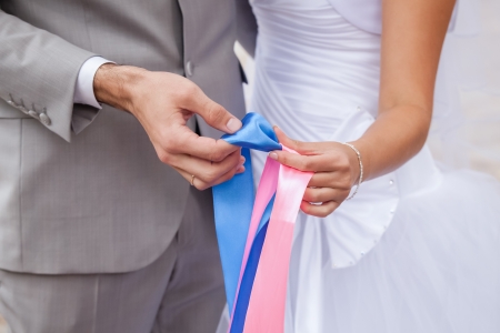 Couple in love holding a ribbon of pink and blue to mark sex of birth.の写真素材