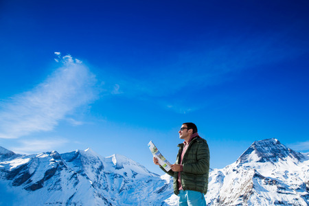 Man with a map looking forward to the background of snowy mountains. Grossglockner, Austriaの写真素材
