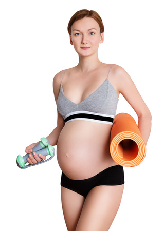 Young pregnant woman with beautiful healthy body holding dumbbells and matの写真素材