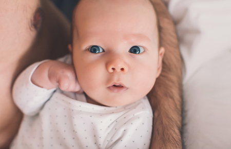 Baby child looking surprised on father's chestの写真素材