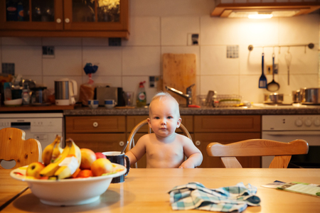 Feeding. Adorable baby child eating with a spoon in high chair. Baby's first solid foodの写真素材