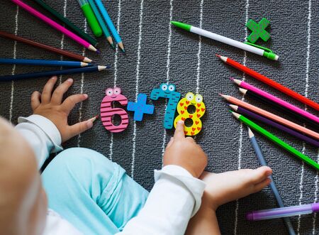 Colorful crayons and figure with small toddler hands. Preschool and kindergarten background. Back to school concept.の写真素材
