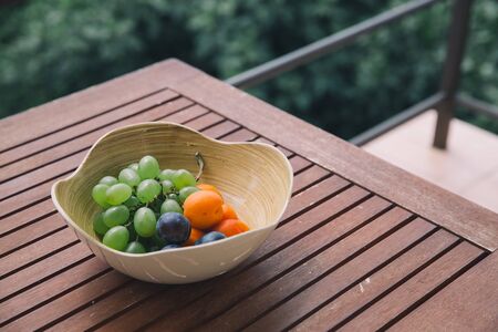 Plate with fresh mixed fruits on the nature background. Assortment of juicy fruits on wooden tableの写真素材