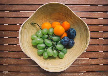 Plate with fresh mixed fruits on the wooden background. Assortment of juicy fruits on wooden tableの写真素材