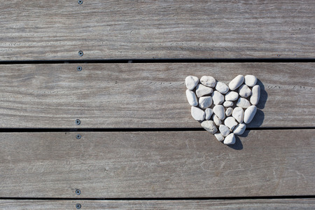 Shape of heart made with stones on the wooden planks of pier background. Love, Zen, Balance, Life Concept.の写真素材