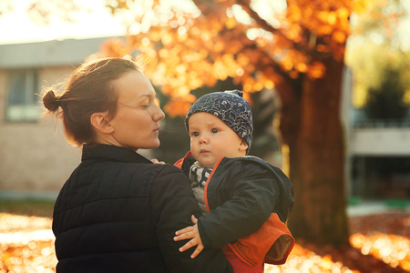 Family in the autumn park. Mom playing with son child in the autumn nature. Mom and her little baby...
