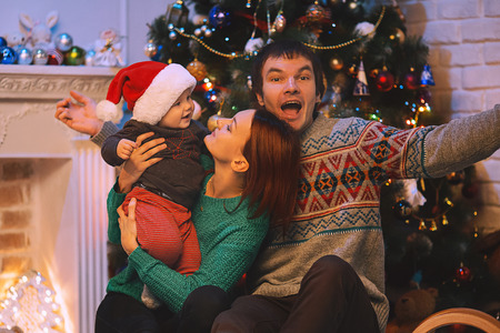 Happy smiling family at a home interior on background of the Christmas tree with gifts.の写真素材