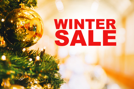 Winter Sale. Christmas gold balls hanging on a Christmas tree on the background of blurred interior shopping center, mall.の写真素材