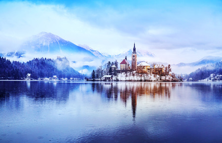 Winter landscape Bled Lake. Travel Slovenia, Europe. Bled Lake one of most amazing tourist attractions. View on snowy Island with Catholic Church in Bled Lake with Castle and Alps in Background.の写真素材