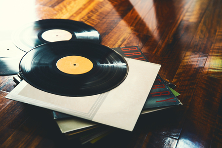 Old vinyl record and a collection of albums on wooden backgroundの写真素材