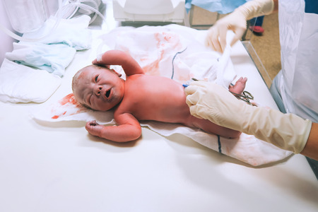 Newborn in nursery after childbirth. Newborn baby in delivery room. Nurse or doctor examining a newborn baby. Mother giving birth to a baby boy.の写真素材