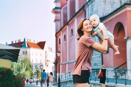 Beautiful young mother with baby child spend time in the old town of Ljubljana, Slovenia, Europe. Mother and son are traveling and walking in a european city.の写真素材