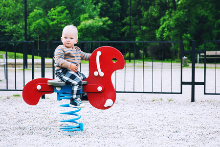 Little Boy Child playing on a playground. Happy family on playground in summer or springtime in a park. Leisure, childhood and people conceptの写真素材