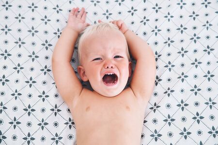 Crying angry little boy in bed. Sad expressions, screaming and crying. Hysteria or crisis in the child.の写真素材