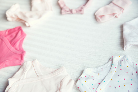 Baby clothes on light pastel fabric background. Gentle, soft and cozy mood. Newborn background with copy space.の写真素材