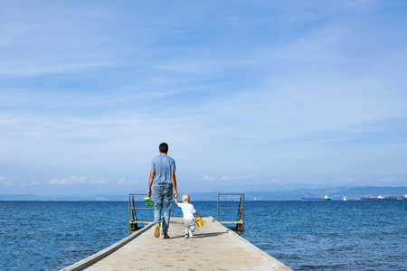 Father with son walking on the sea pier. Family background. Lifestyle concept. Parent and child together.の写真素材