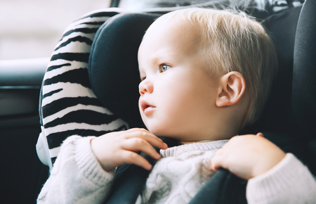 Child transportation safety. Portrait of toddler boy sitting in car seat. Kid looking in window of car.の写真素材