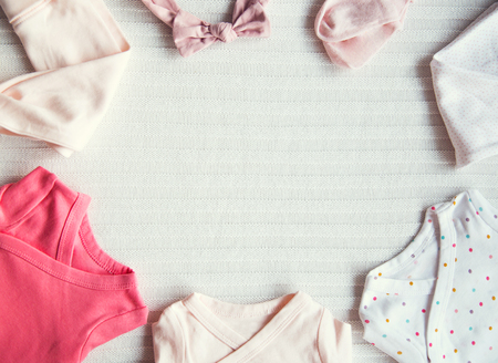 Baby clothes on light pastel fabric background. Gentle, soft and cozy mood. Newborn background with copy space.の写真素材