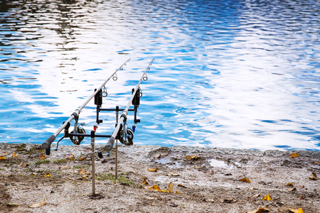 Fishing rods on the bank of Lake Bled, Slovenia. Fishing background. Two spinning on the background of smooth water surfaceの写真素材
