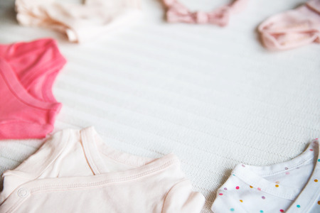 Baby clothes on light pastel fabric background. Gentle, soft and cozy mood. Newborn background with...