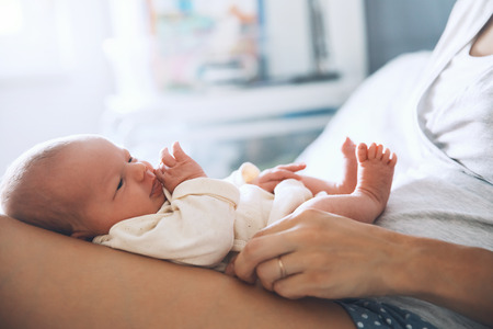 Newborn baby sleep first days of life at home. Young mother holding her new born child. Beautiful mom lying at bed with a cute little baby.の写真素材