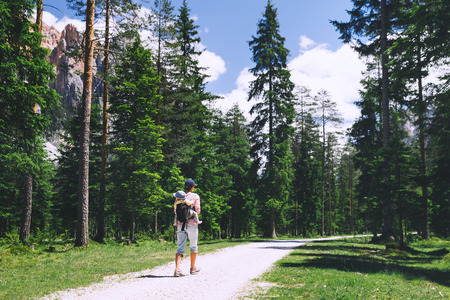 Family on trekking day in the mountains. Mother and child on nature. Tourists travel at Dolomites, Italy, Europe. Summer holiday in South Tyrol. Woman hiking with baby in carrier backpackの写真素材