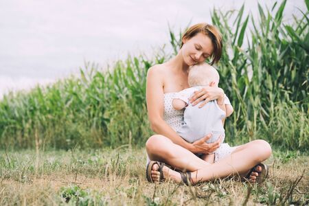 Mother and baby outdoors. Family on nature. Loving woman with child in countryside. Photo of natural parenthood, maternity leave. Theme of zero waste, slow fashion and conscious life, eco lifestyleの写真素材