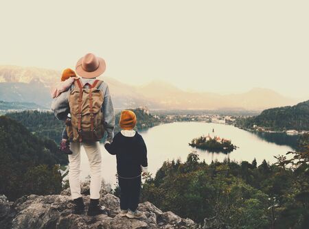 Journey Slovenia with kids. Family travel Europe. Hiker woman with children on Bled Lake among nature and Alps mountains. Traveling mother with backpack with her kids at autumn or winter vacationの写真素材