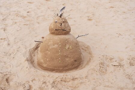 New Year or Merry Christmas sandy snowman on tropical ocean sand beach. Background lifestyle image of winter vacation in warm countries. Family holiday on Tenerife, Spain.の写真素材