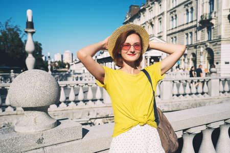 Travel or study in Slovenia, Europe. Young smiling girl in sunglasses on Triple Bridge in Ljubljana Old Town at summer. Woman tourist on background of city architecture. Local living in Ljubljanaの写真素材