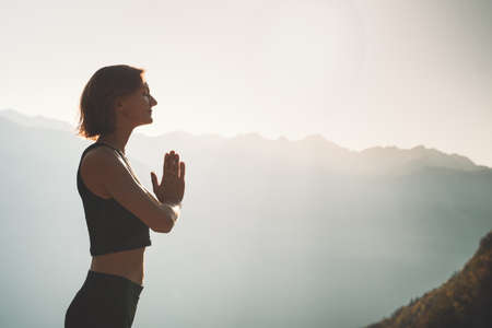 Image of yoga inspiration on nature. Young woman with yoga mat gets ready to practicing yoga outdoor. Beautiful female with slim, strength body in white clothes. Healthy and conscious lifestyles.の写真素材