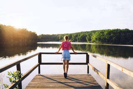 Woman wearing glasses using smartphone while working on computer from home. Female entrepreneur small business responding on emails or calls from clients. Modern creative workplace.の写真素材