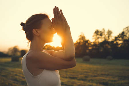 Image of yoga inspiration on nature. Young woman with yoga mat gets ready to practicing yoga outdoor. Beautiful female with slim, strength body in white clothes. Healthy and conscious lifestyles.の写真素材