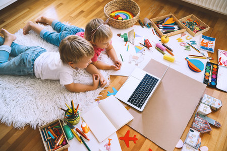Kids drawing and making crafts with online art classes at home. Children using laptop to distance online education. Background for preschool, kindergarten or family daycare. Childcare and technology.の写真素材