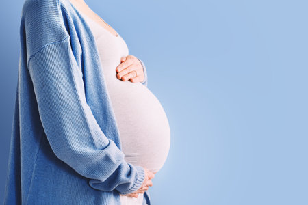Beautiful pregnant woman hugging her belly in white background. Expectant mother waiting for baby birth during pregnancy. Concept of maternal health, visiting doctor and gynecological checkup.の写真素材