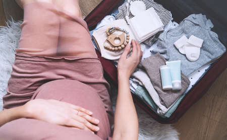 Pregnant woman hugging belly and packing maternity hospital bag. Beautiful mother during pregnancy...