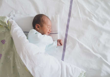 Newborn baby peacefully sleeping in hospital room after delivery. First days life of baby after...